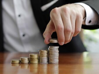 closeup-shot-businessman-s-hands-counting-stacks-coins-after-business-success