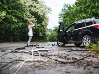 Young woman standing by the damaged car after a car accident.